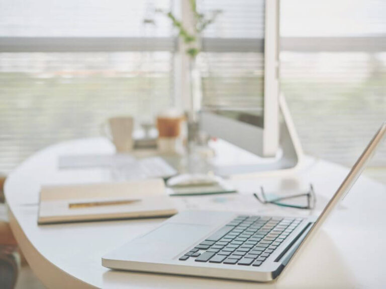 clean view of laptop on desk with window in background.